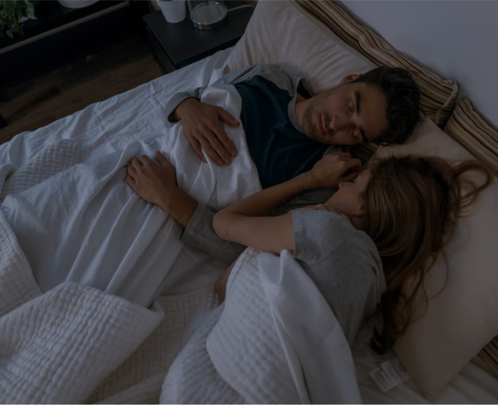 A couple asleep in a dark room on an Essentia Mattress